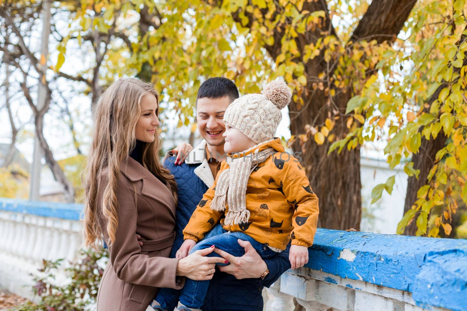 a family with a boy walking in the autumn Park happiness by Simakov