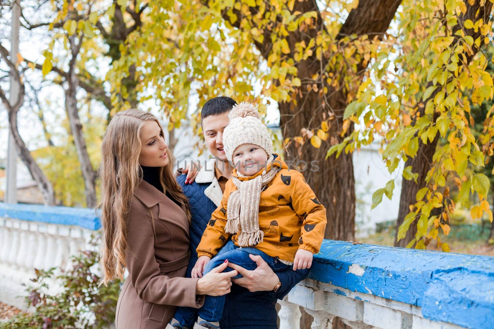 a family with a boy walking in the autumn Park happiness by Simakov