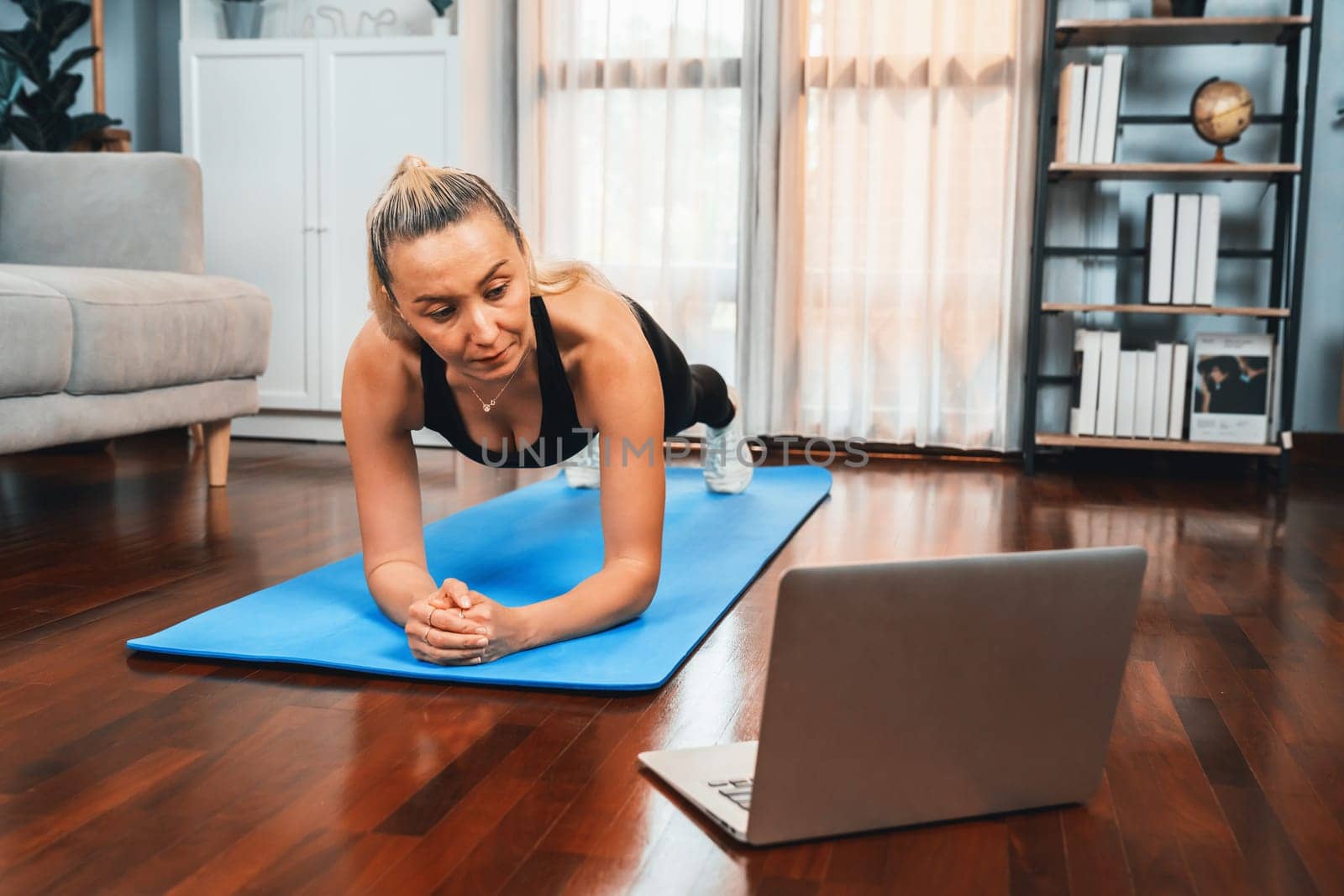 Athletic and sporty senior woman planking on fitness exercising mat while watching online fitness video at home exercise as concept of healthy fit body lifestyle after retirement. Clout