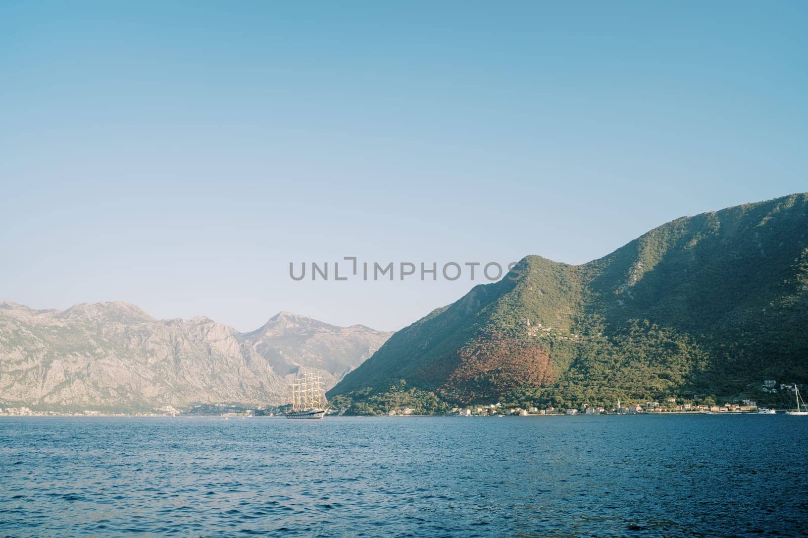 Large ship sails on the sea against the backdrop of green mountains. High quality photo