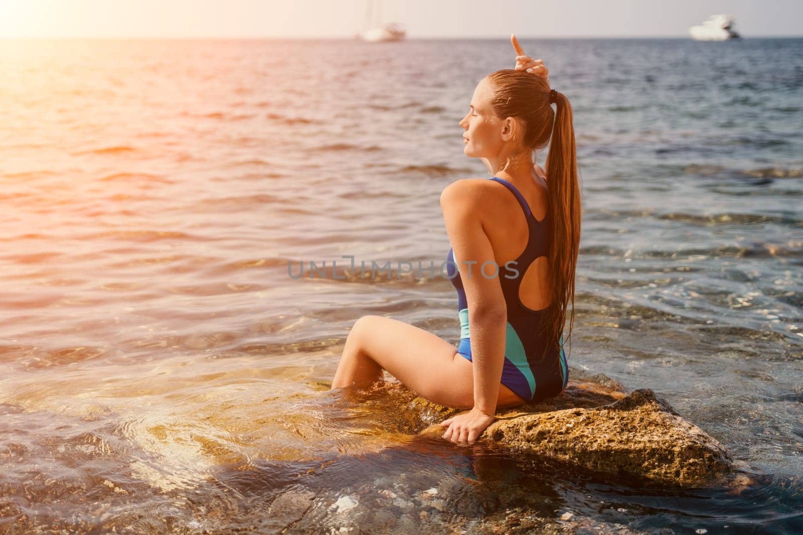Woman travel sea. Happy tourist in blue swimwear takes a photo outdoors to capture memories. woman traveling and enjoying her surroundings on the beach, with volcanic mountains in the background. by panophotograph