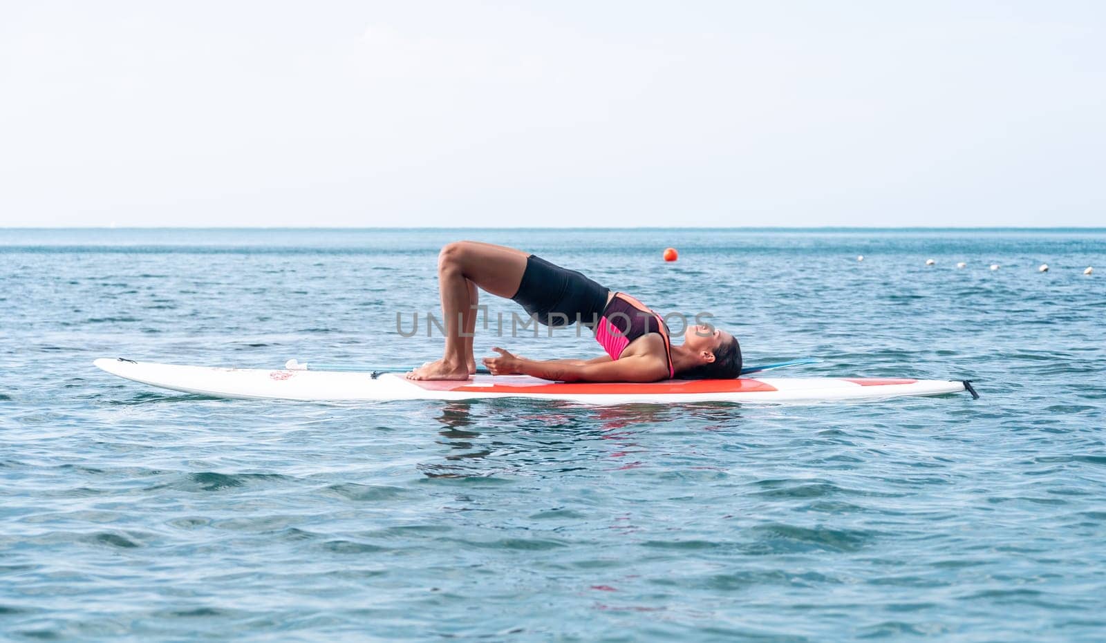 Woman sup yoga. Happy young sporty woman practising yoga pilates on paddle sup surfboard. Female stretching doing workout on sea water. Modern individual female outdoor summer sport activity