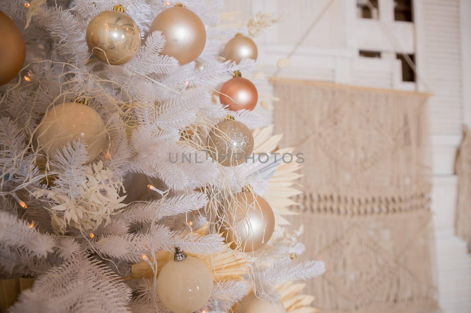 Close up of beautiful fir branches with shiny golden, silver and white baubles or balls, xmas ornaments and garland lights