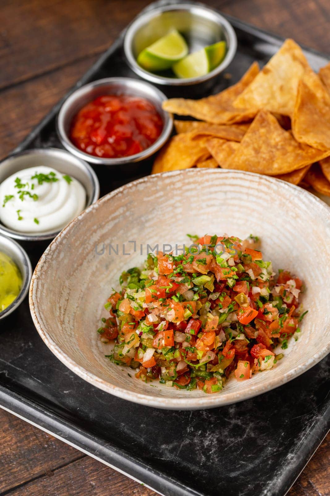 Pico de gallo from Mexican cuisine with dipping sauces on wooden table