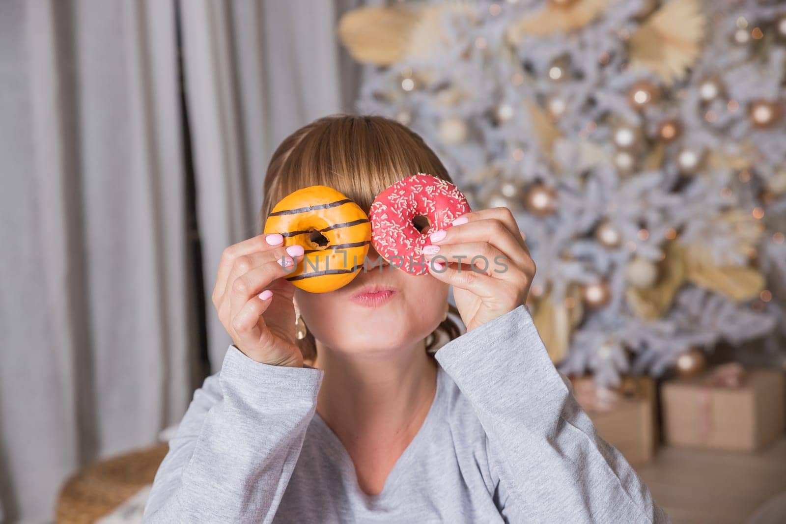 cheerful young woman holds donuts in her hands in the winter forest, the concept of winter holidays