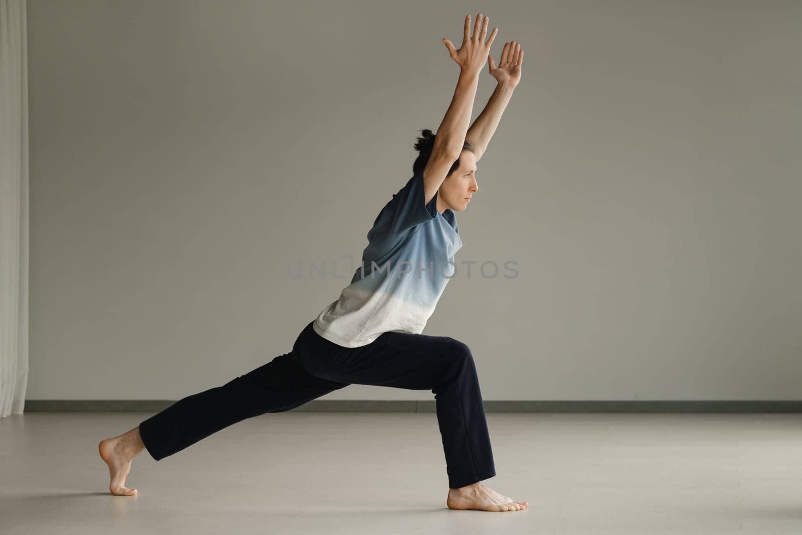 a man in a sports uniform does yoga in a fitness room. the concept of a healthy lifestyle by Lobachad