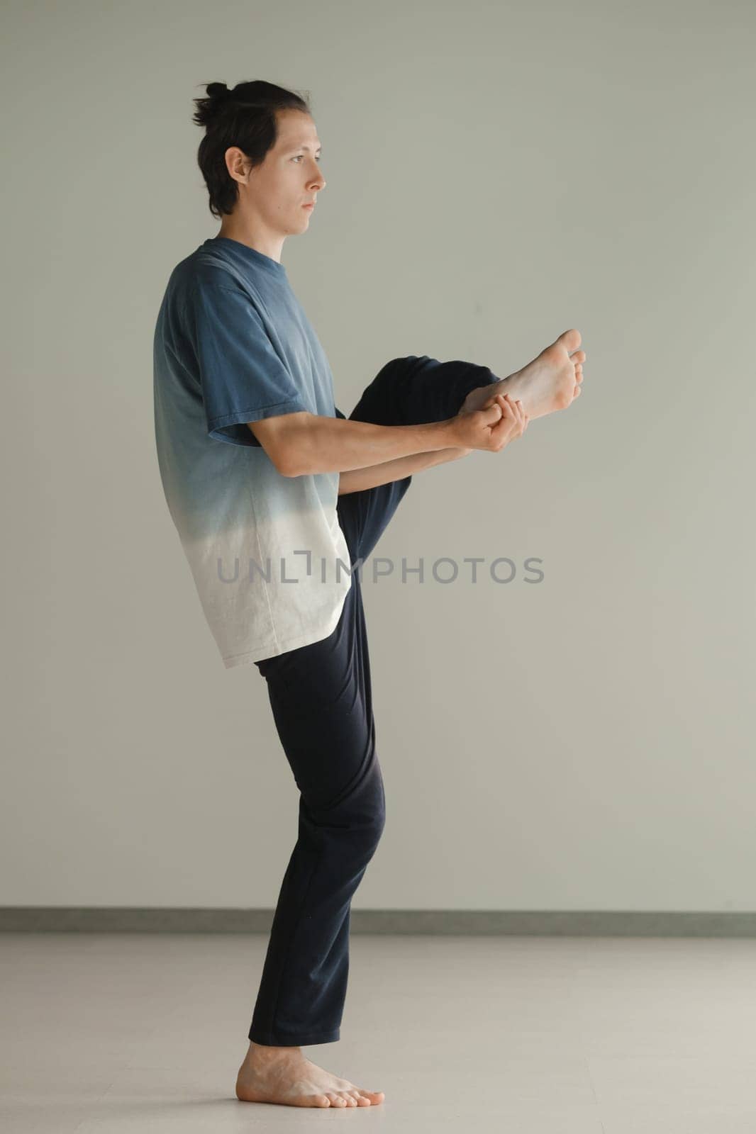 a man in a sports uniform does yoga in a fitness room. the concept of a healthy lifestyle by Lobachad