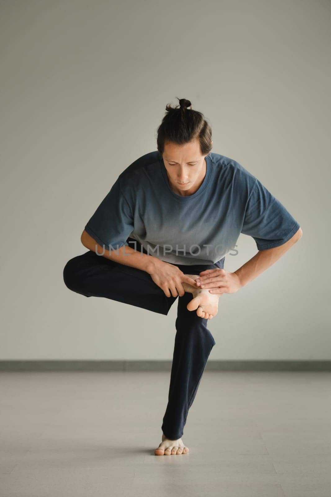 a man in a sports uniform does yoga in a fitness room. the concept of a healthy lifestyle by Lobachad