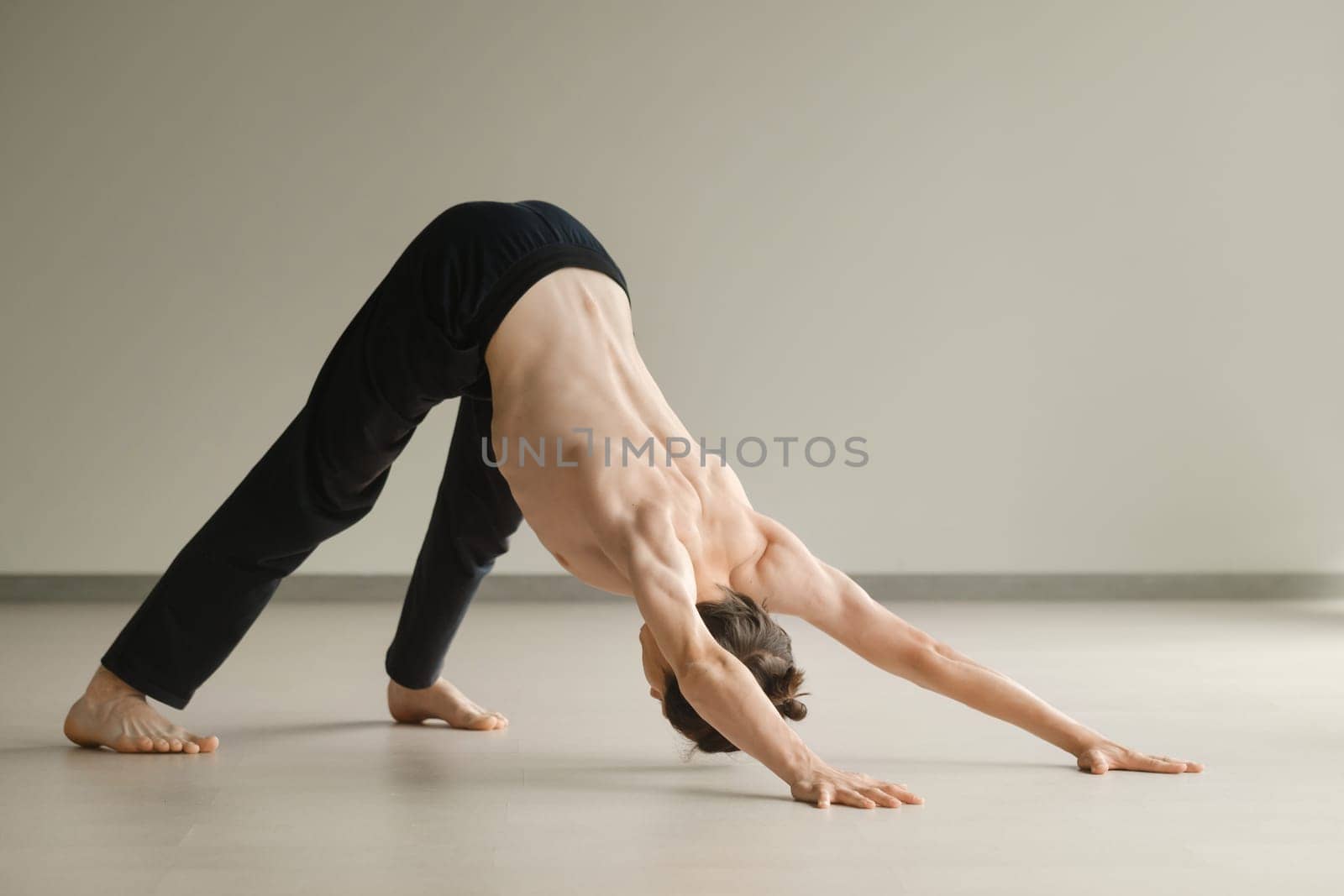 a man with a naked torso does yoga in the gym. the concept of a healthy lifestyle by Lobachad