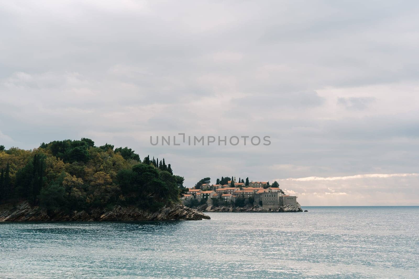 View from the sea and rocky shore to the island of Sveti Stefan. Montenegro. High quality photo