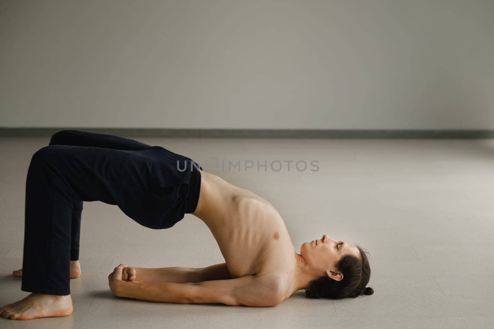 a man with a naked torso does yoga in the gym. the concept of a healthy lifestyle by Lobachad
