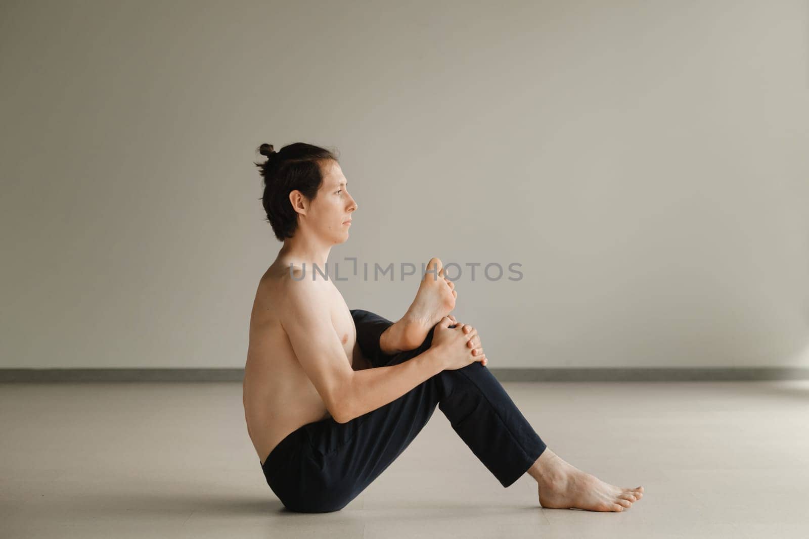 a man with a naked torso does yoga in the gym. the concept of a healthy lifestyle by Lobachad