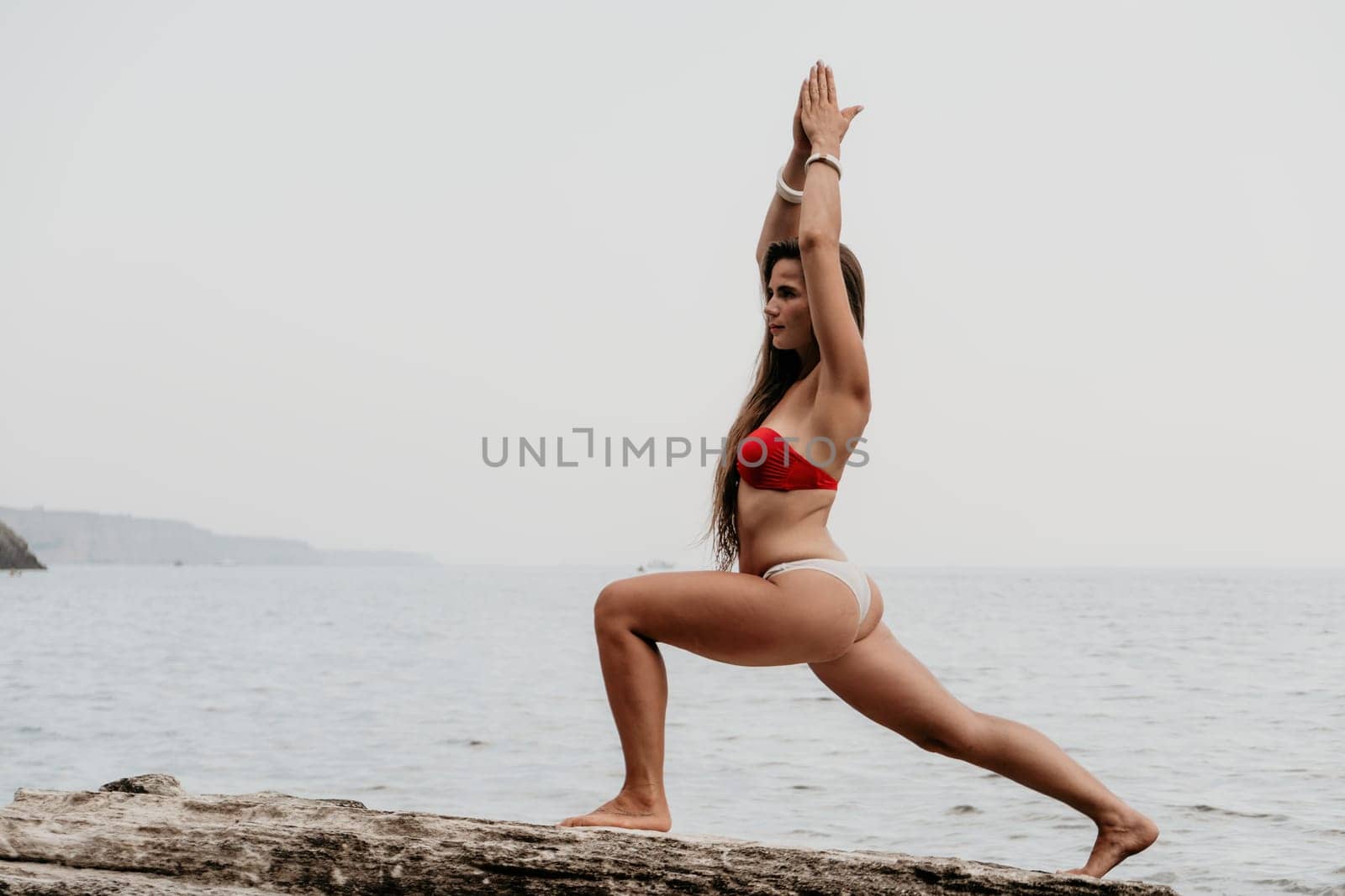 Woman meditating in yoga pose silhouette at the ocean, beach and rock mountains. Motivation and inspirational fit and exercising. Healthy lifestyle outdoors in nature, fitness concept.