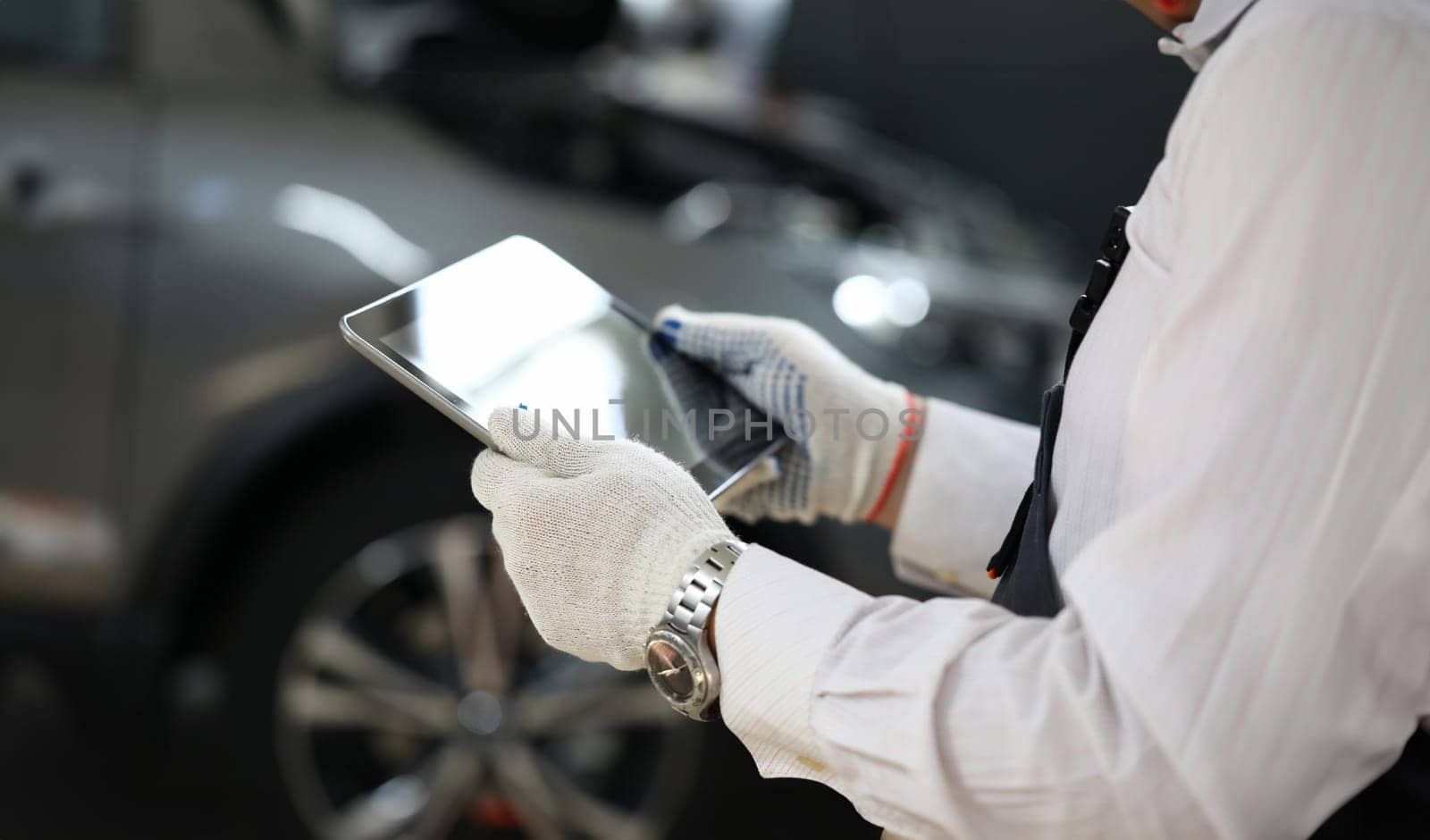 Male master locksmith holds tablet and performs car diagnostics. Apps for car repair concept