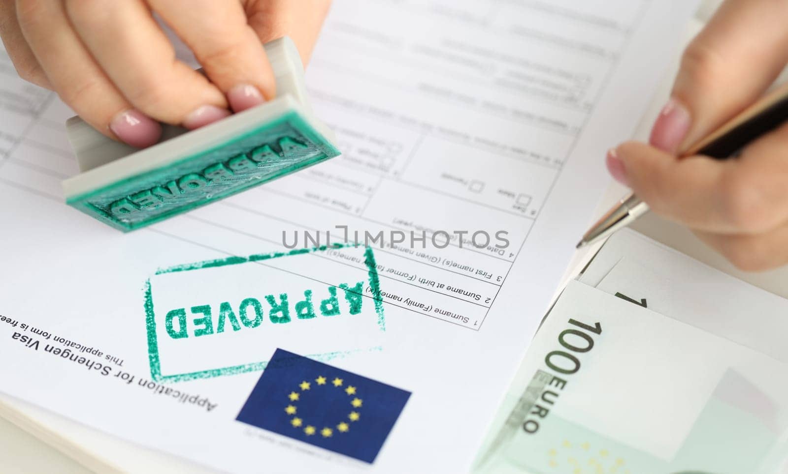 Approval of visa for travel to European Union, an employee of embassy puts stamp. Getting Schengen visa concept