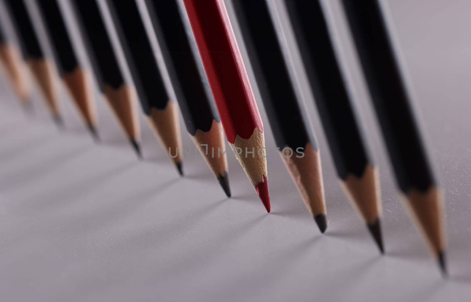 One red pencil is set of identical black counterparts. Uniqueness of business ideas and creative creative approach