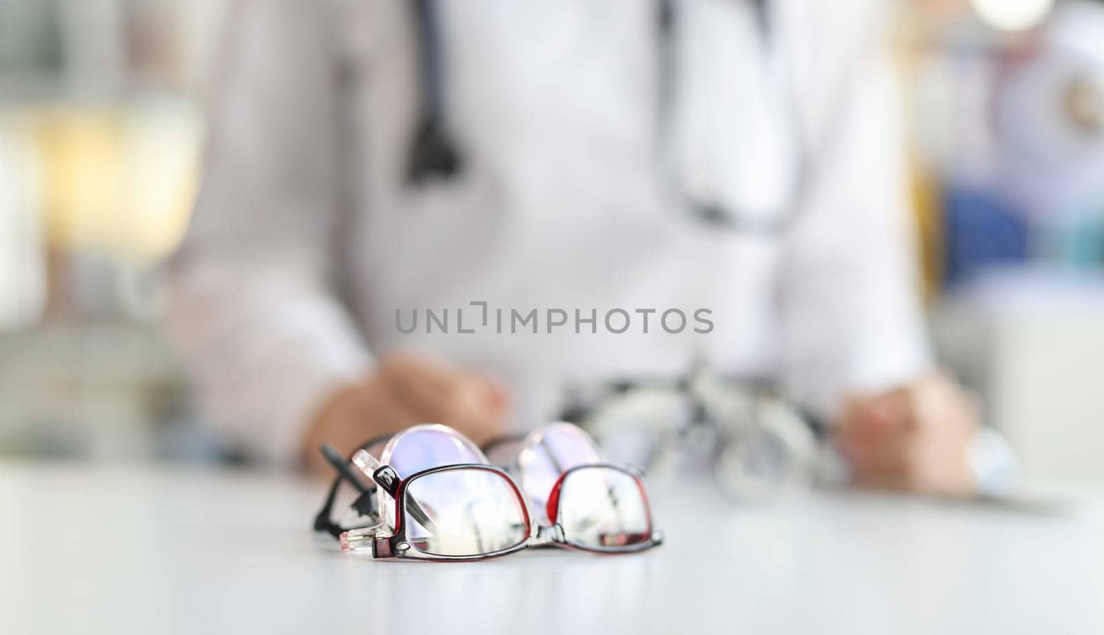Ophthalmologist sits in background with various glasses for fitting lenses in frame. Treatment of farsightedness myopia and astigmatism