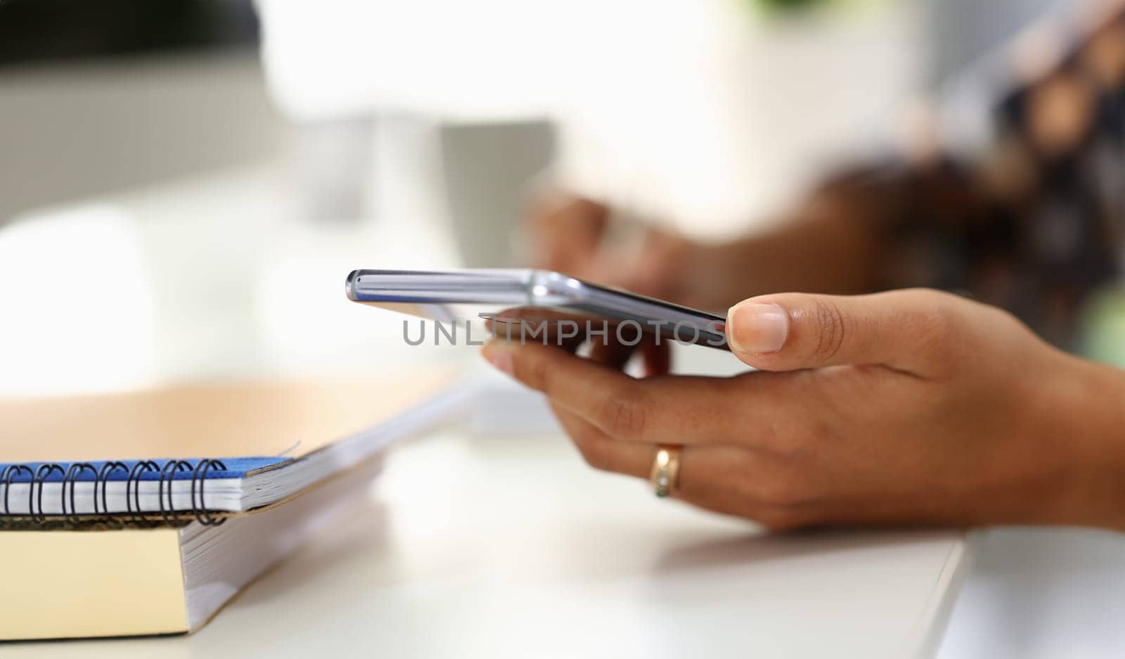 Student writes in notebook and holds smartphone. Woman hands taking notes using online organizer app on mobile phone concept