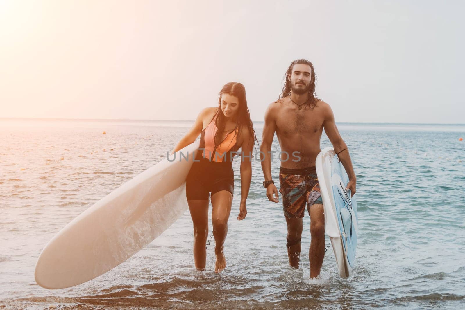 Sea woman and man on sup. Silhouette of happy young woman and man, surfing on SUP board, confident paddling through water surface. Idyllic sunset. Active lifestyle at sea or river