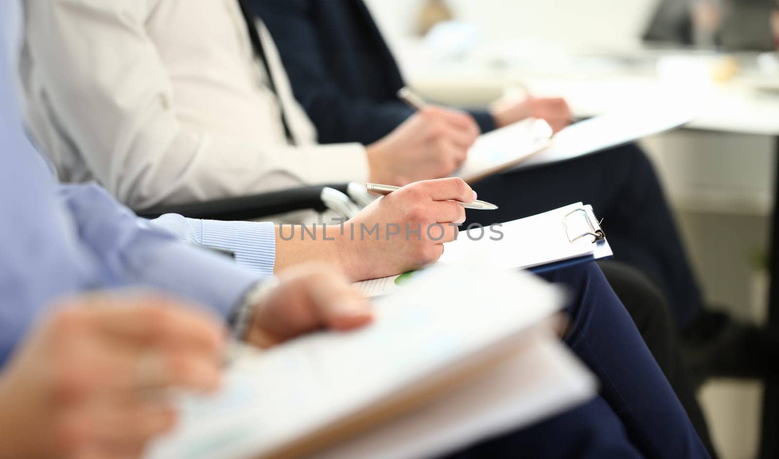 Businessmen are holding documents while taking notes at seminar. Educational conference and business meeting concept