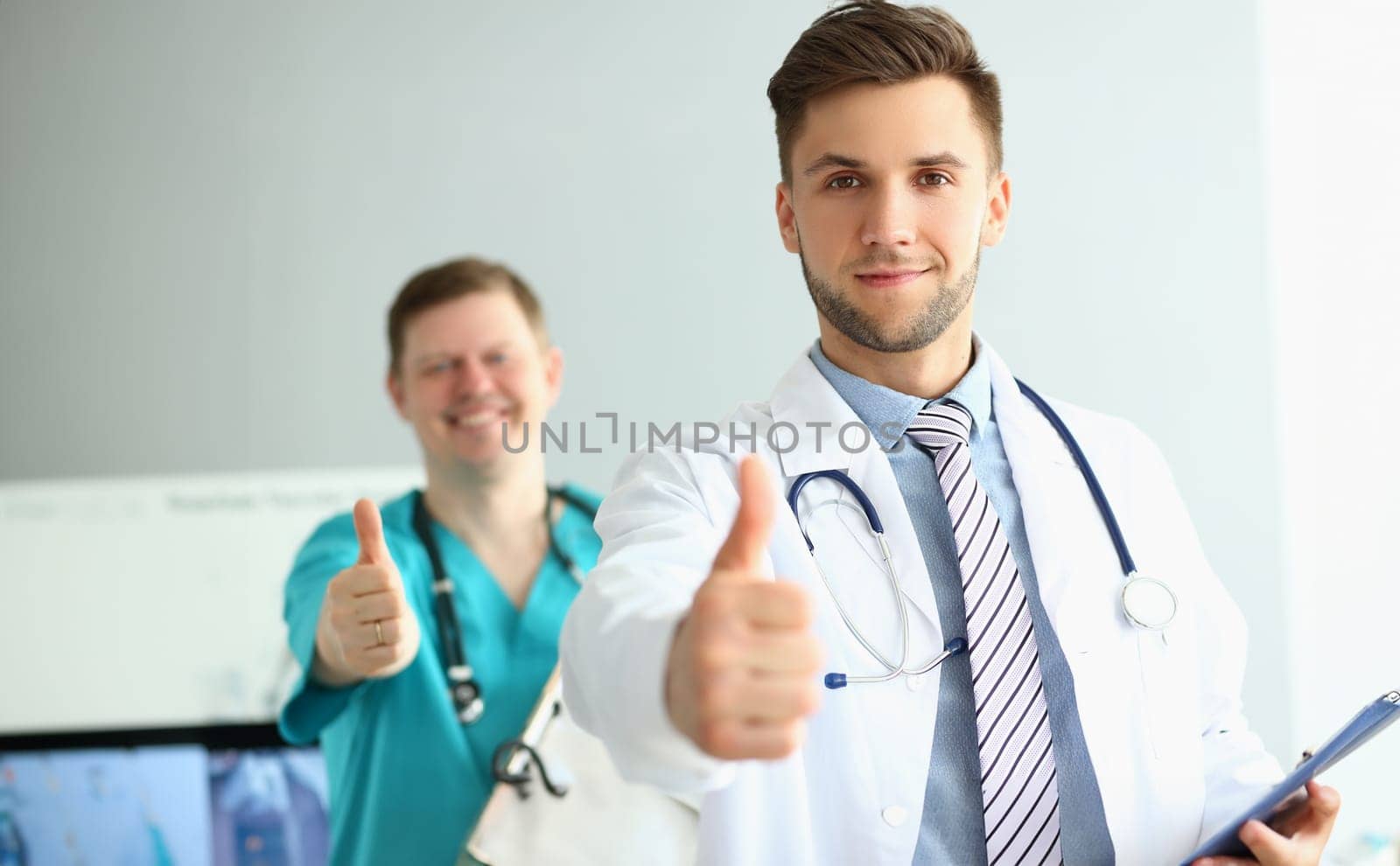 Two doctors gesture thumbs up in clinic recommending medical services. Health insurance and quality services concept