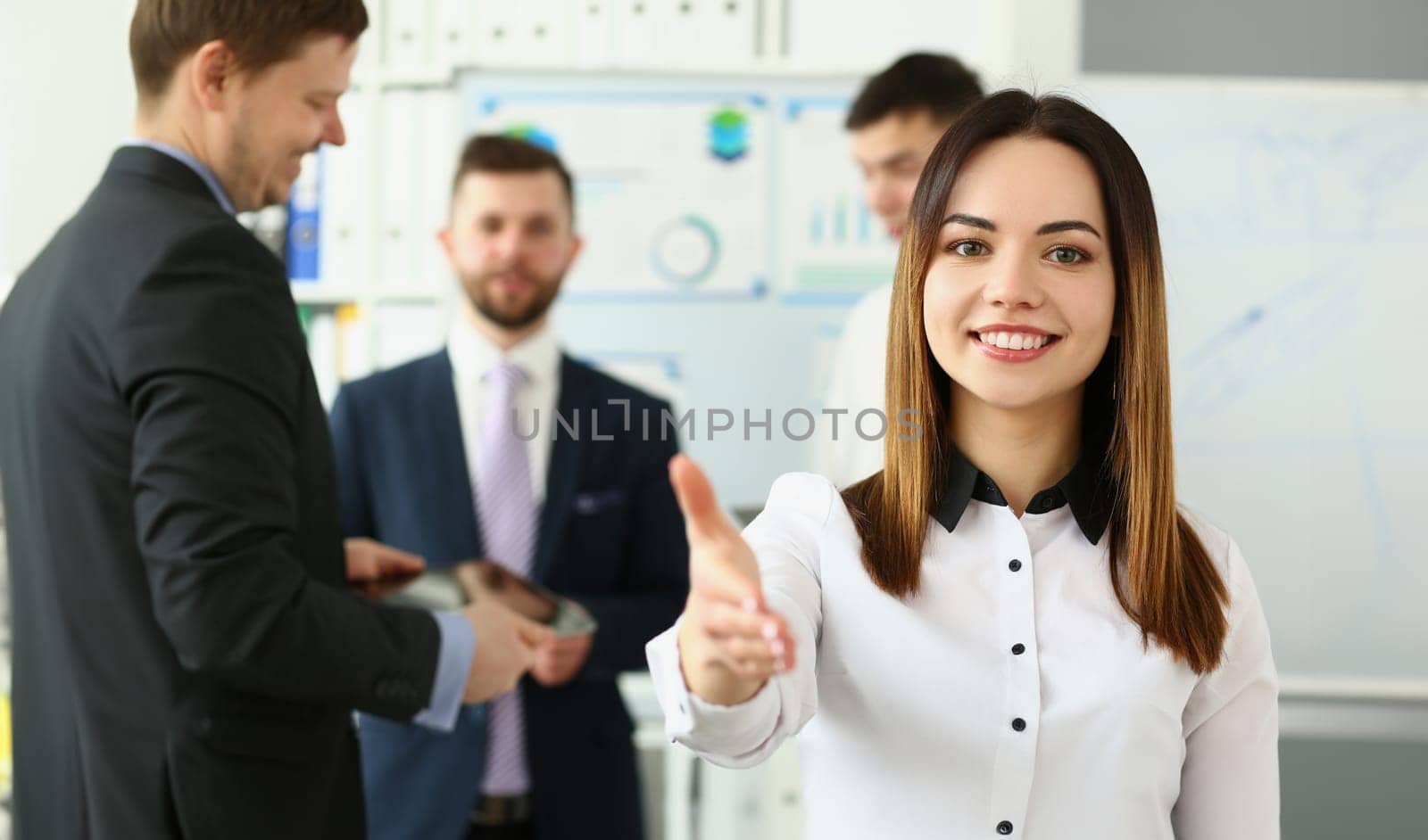 Businesswoman holds out hands for handshake and business team by kuprevich