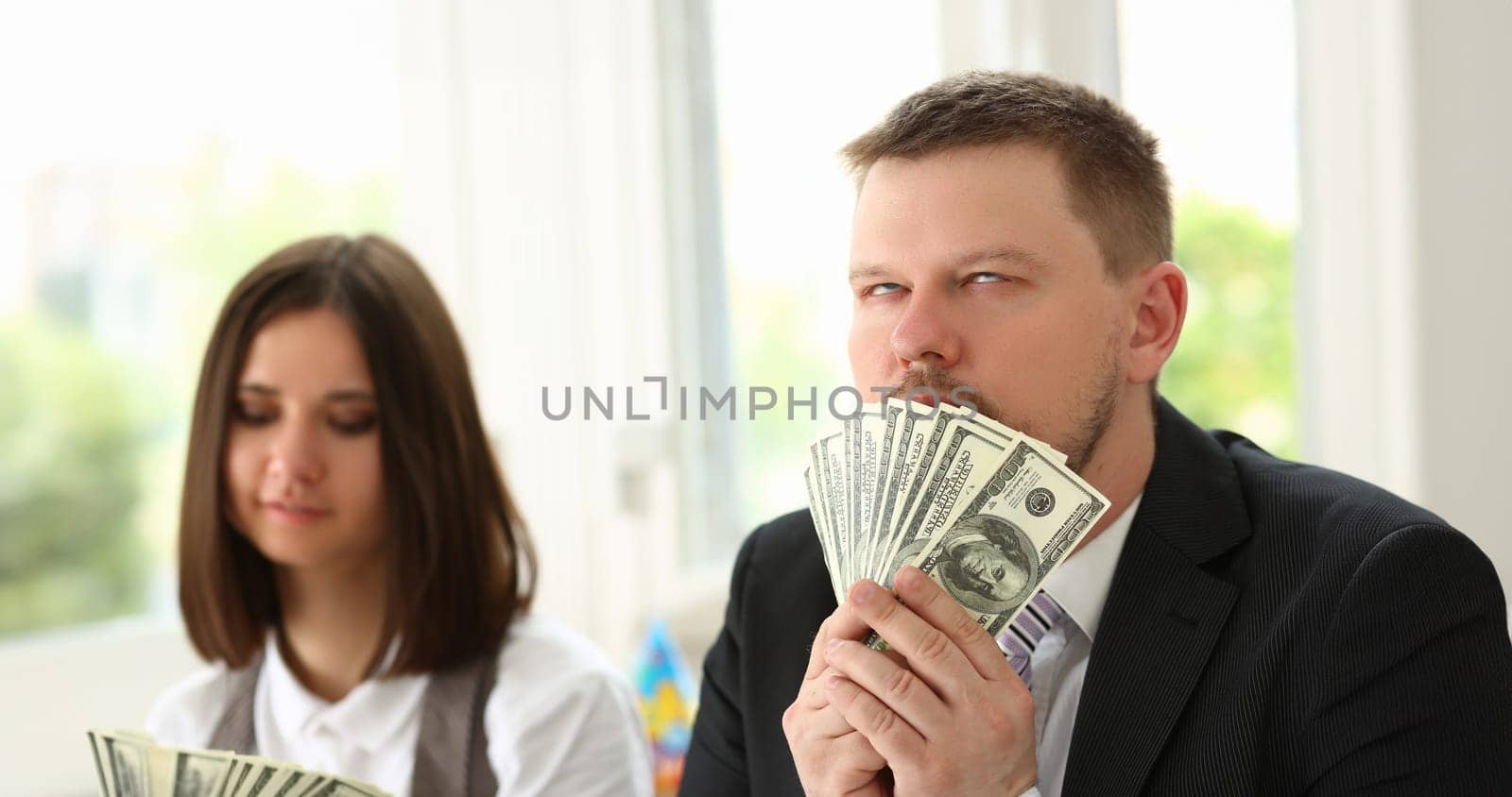 Man holds up dollars banknotes and enjoys success of financial income and growth. Emotion high from money concept