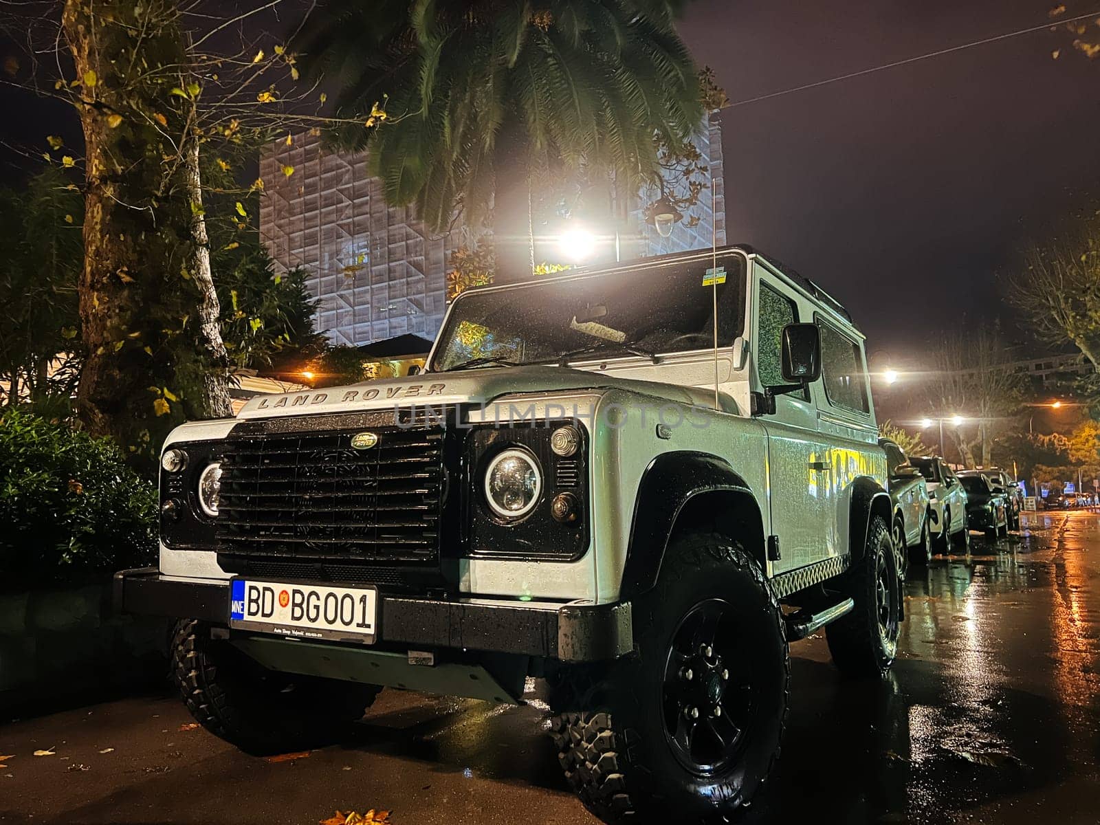 White SUV stands in the parking lot under a street lamp. Logo: Land Rover. High quality photo