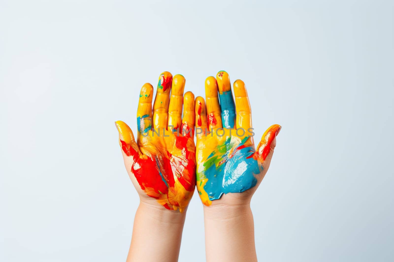 Child's hands in multi-colored paints on a white background.