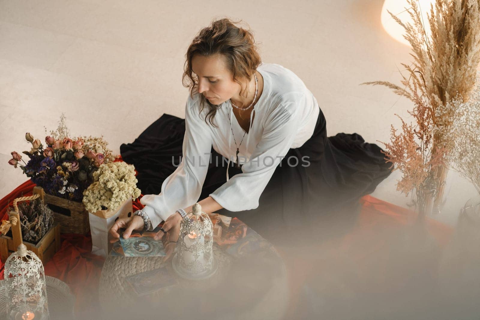 Women's circle and practice in the use of metaphorical cards. The girl is sitting surrounded by flowers.