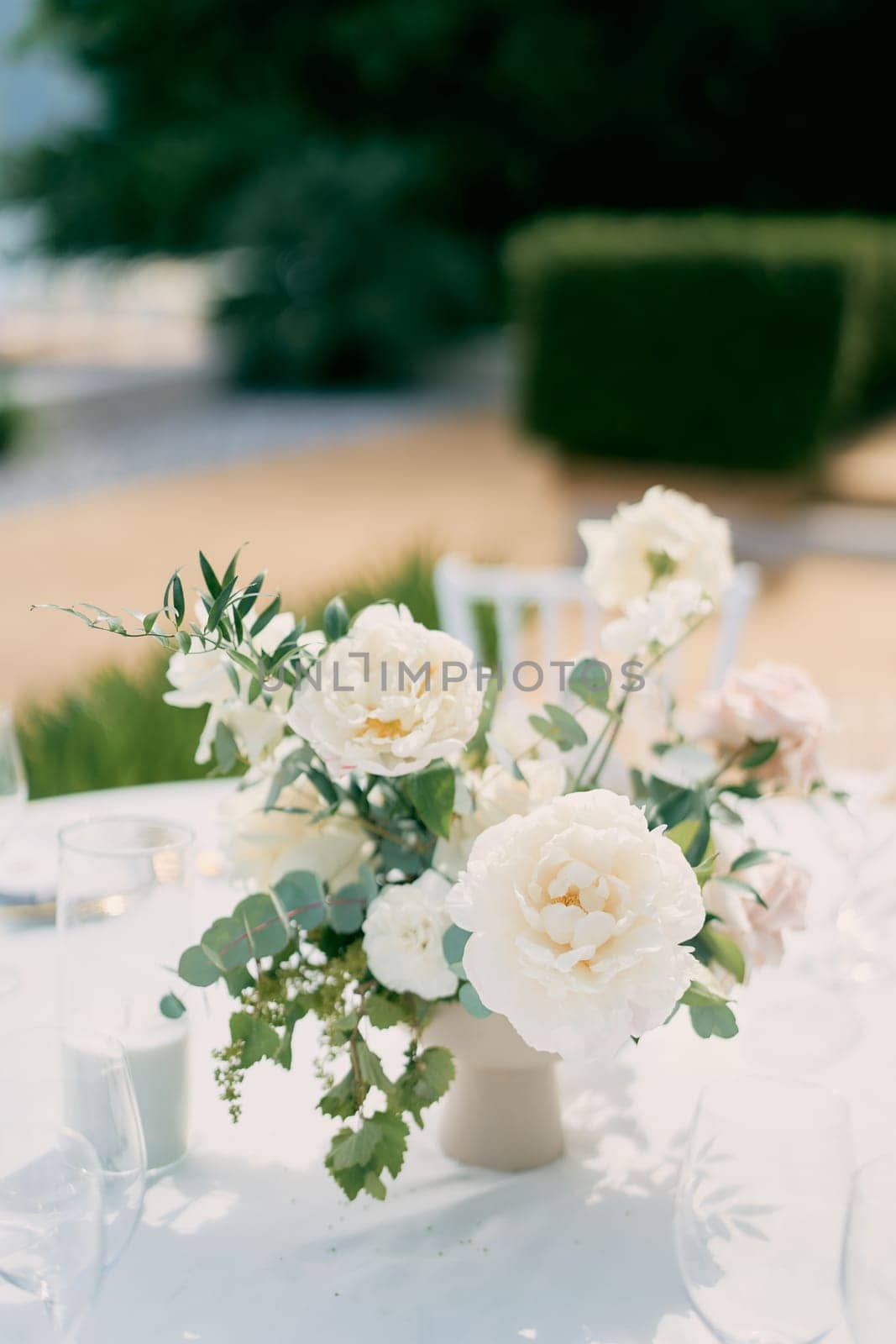 Lush bouquet of flowers stands on a festive table in the garden by Nadtochiy