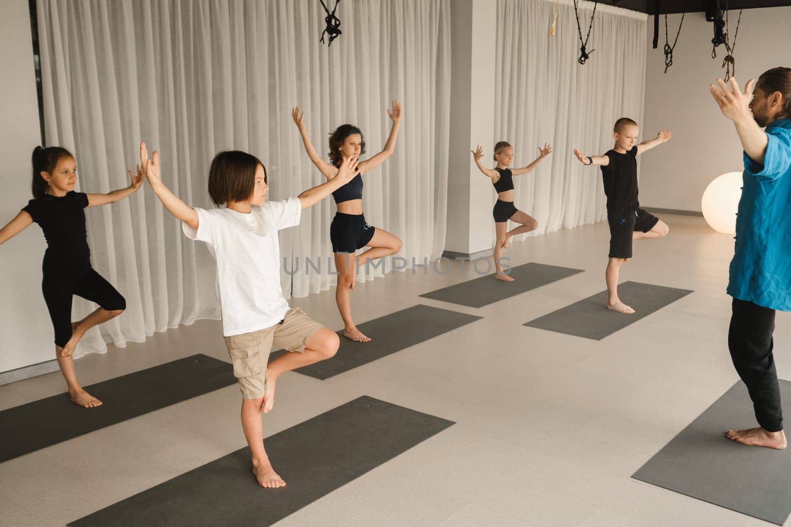 Children do yoga in the gym under the guidance of an instructor. Children's gymnastics by Lobachad
