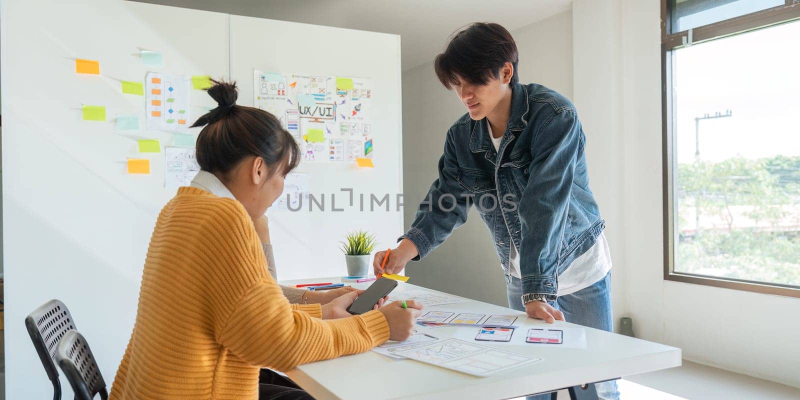 Ux developer and ui designer use augmented reality brainstorming about mobile app interface wireframe design on desk at modern office. creative digital development agency.