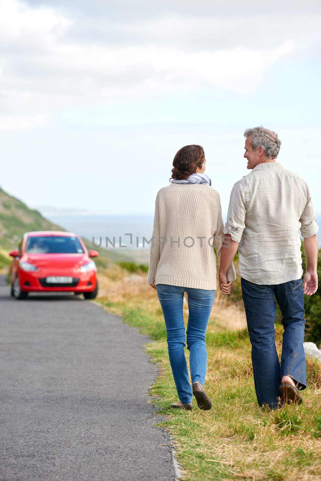 Old couple, walking and holding hands in nature on holiday, vacation or retirement with support. Back, man and woman with love, car and happiness in marriage together on a road trip or journey by YuriArcurs