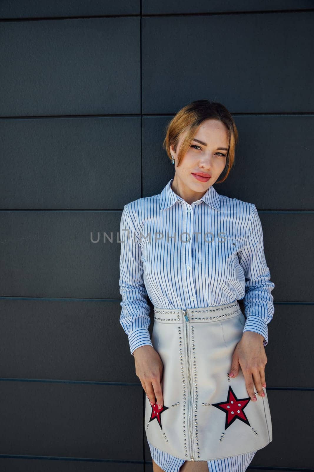 Beautiful fashionable woman standing against dark brick textured wall walk