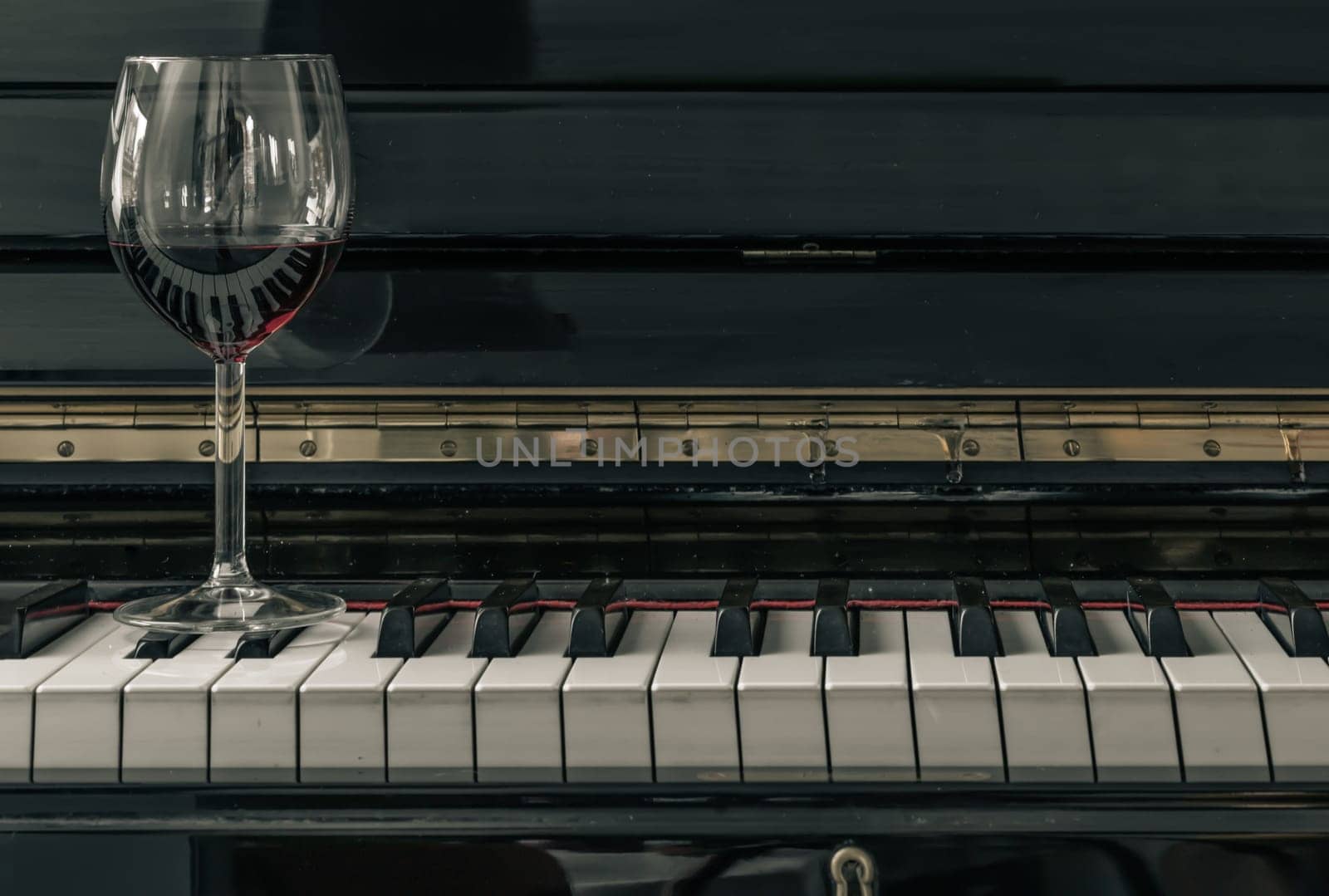 Glass of red wine on piano keyboard. Music and wine concept, Copy space, Selective focus.
