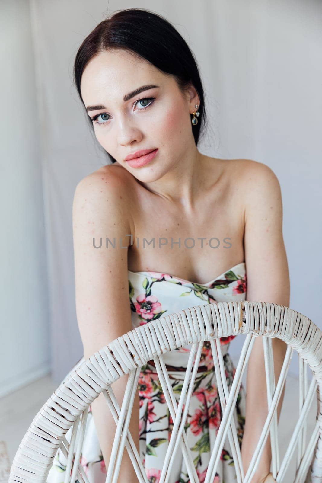 brunette woman in a floral dress near the chair