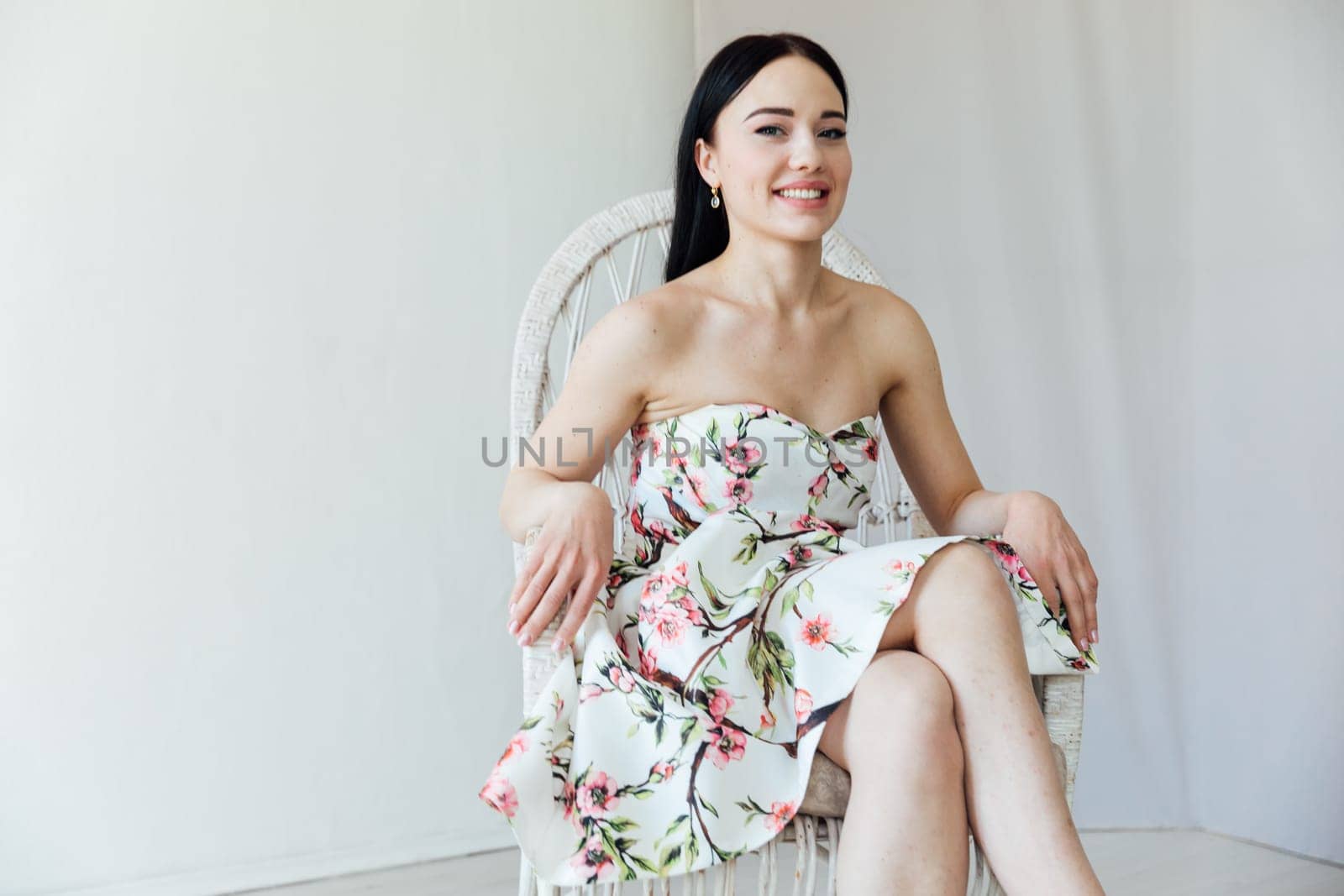 Beautiful brunette woman in floral dress sitting on chair by Simakov