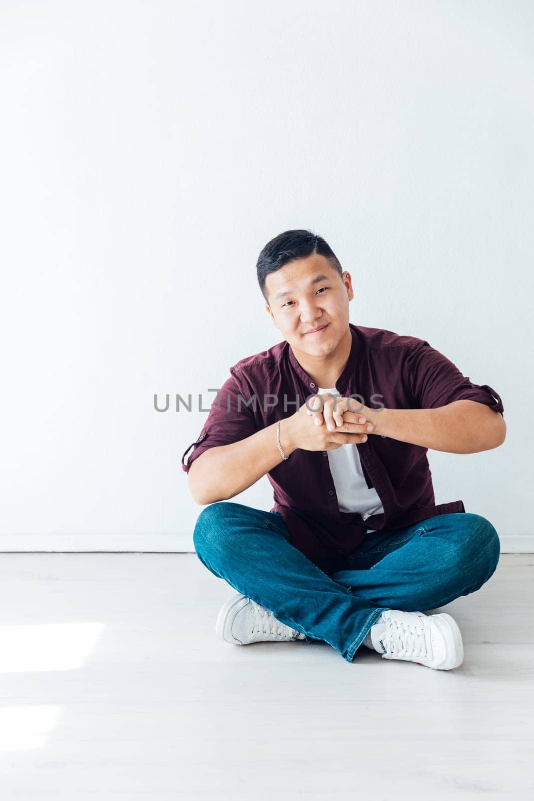 A man sits on the floor on a white background