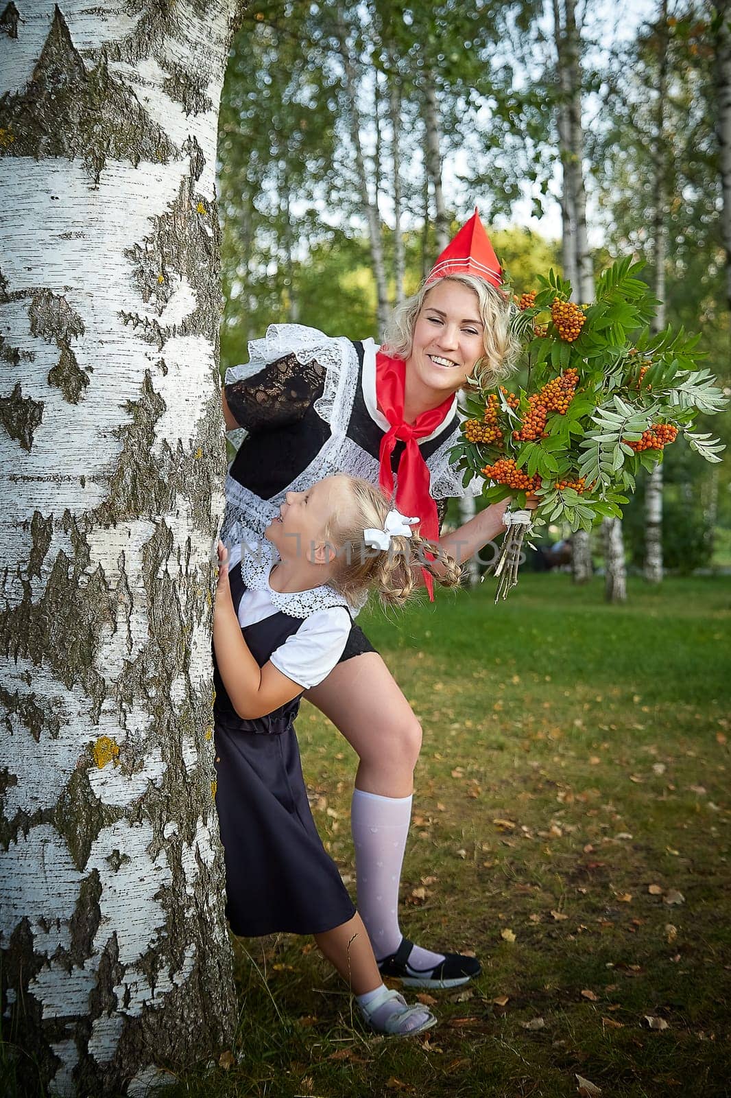 Young and adult schoolgirl on September 1, mother and daughter having fun together. Generations of schoolchildren of USSR and Russia. Female pioneer in red tie and October girl in modern uniform by keleny