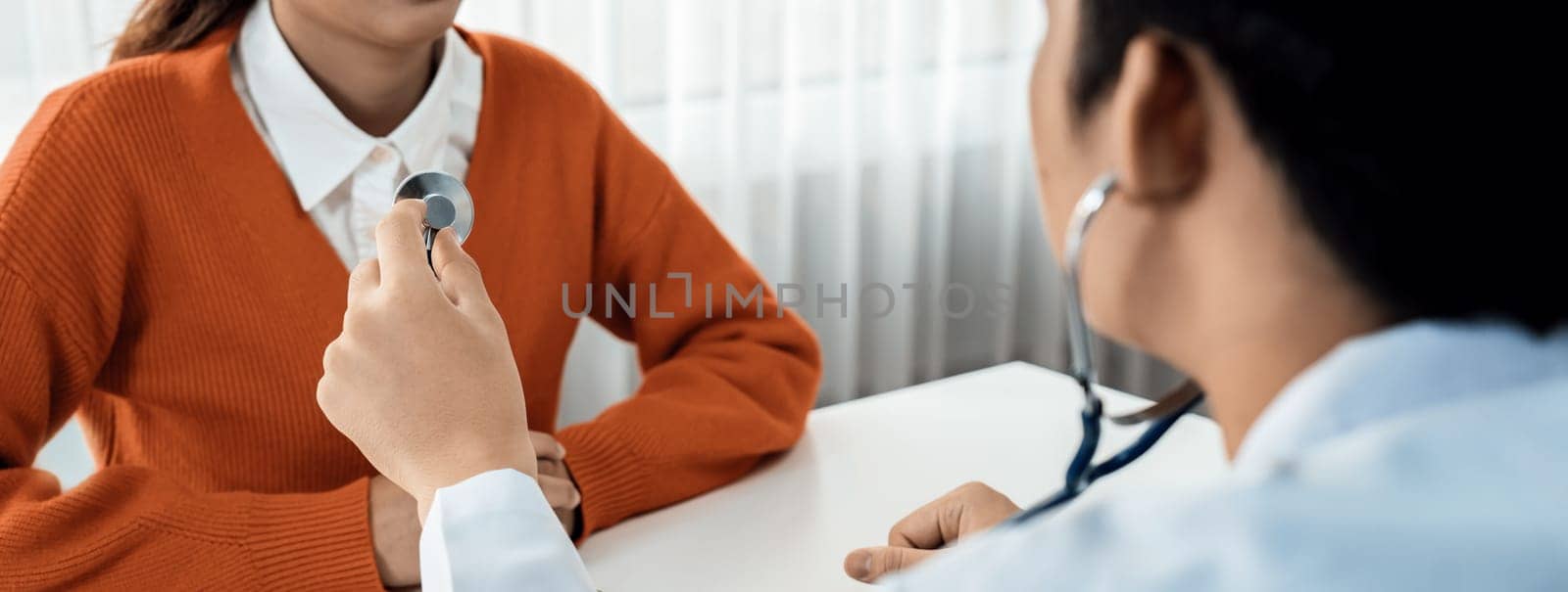 Patient attend doctor's appointment at clinic or hospital office. Doctor examining and diagnosis symptoms while checking the patient's pulse with stethoscope. Panorama Rigid