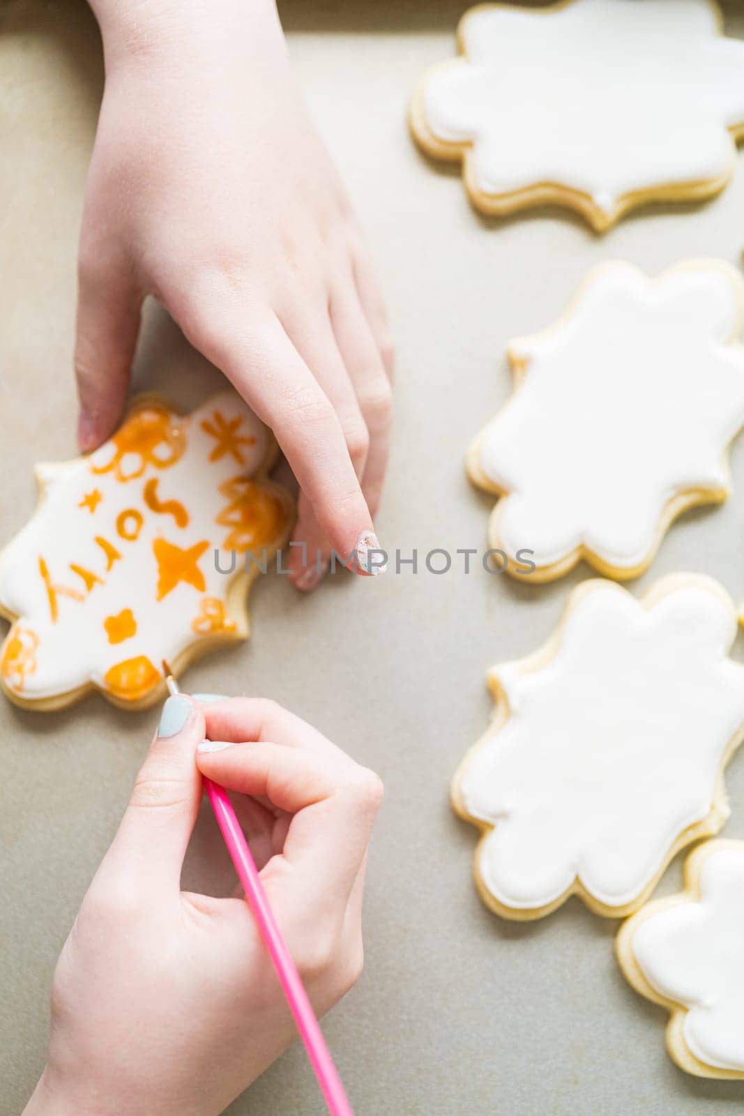 A heartwarming scene of a little girl carefully writing 'Sorry' on sugar cookies with food coloring, the cookies beautifully flooded with white royal icing.