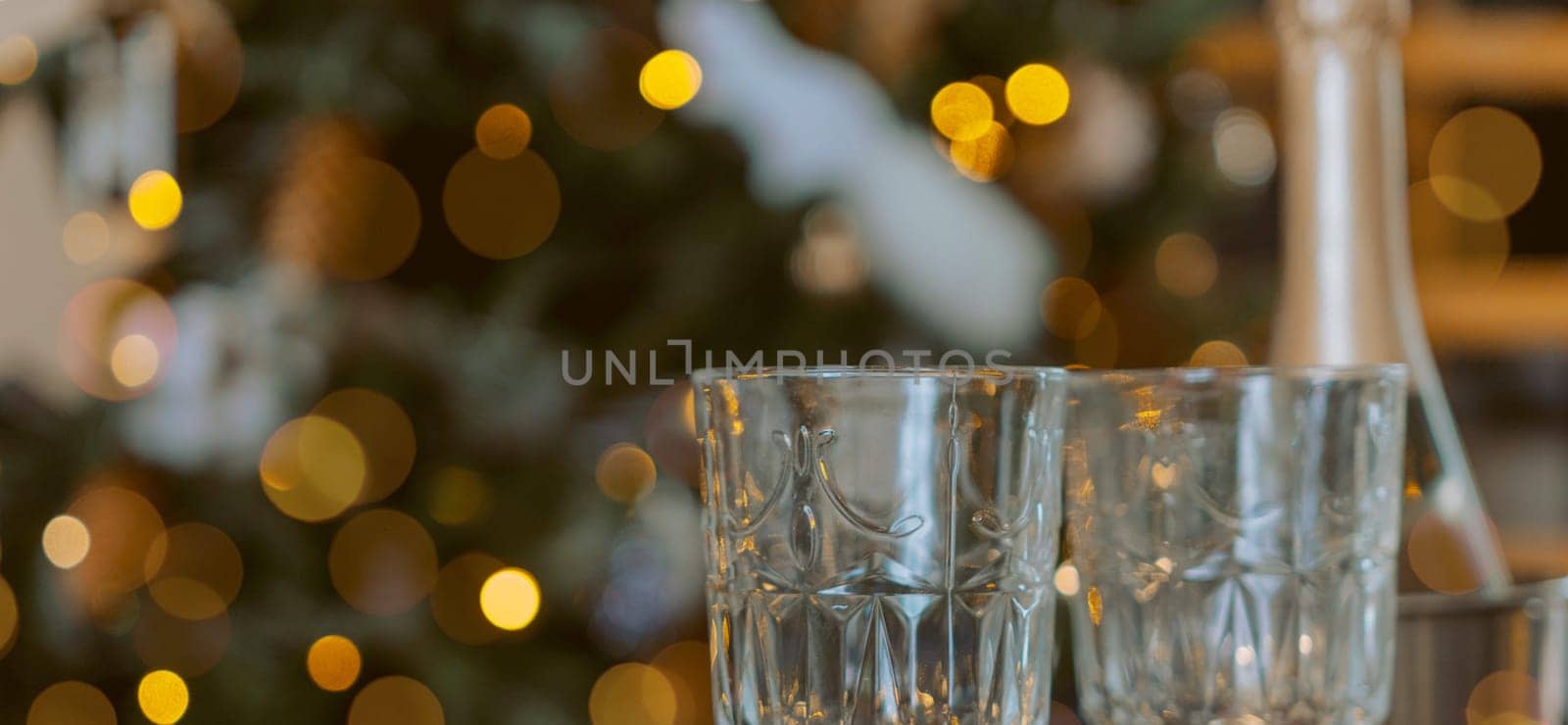 Champagne glasses, New Year decor. New Year's festive setting, family holidays.Two glasses of champagne are on the table against the background of New Year's decorated tree