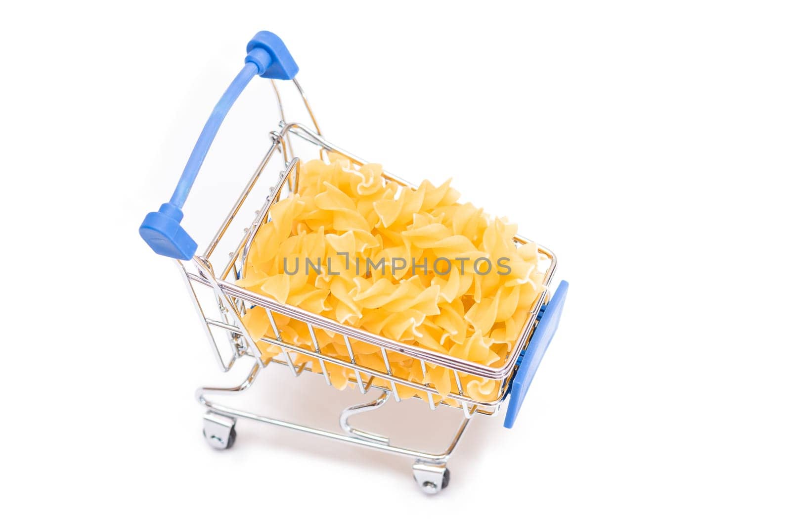 Uncooked Fusilli Pasta in Small Shopping Cart Isolated on White Background. A Crisis: Buying Cheap Food. Classic Dry Spiral Macaroni. Italian Culture and Cuisine. Raw Pasta - Isolation