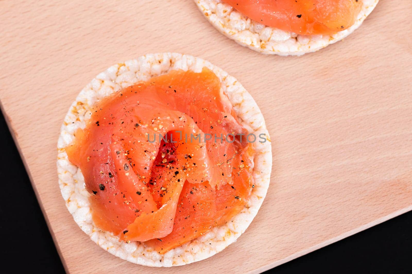 Tasty Rice Cake Sandwiches with Fresh Salmon Slices on Cutting Board - Top View. Easy Breakfast and Diet Food. Crispbread with Red Fish. Healthy Dietary Snack