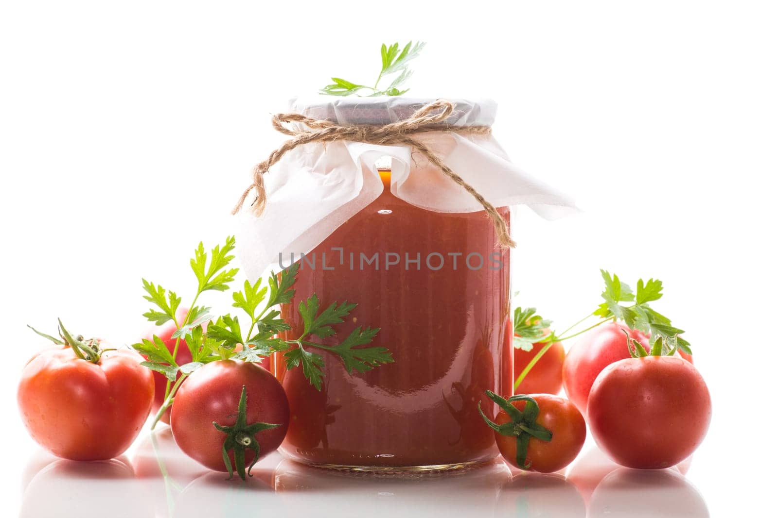 Cooked homemade tomato juice canned in a jar of natural tomatoes, isolated on white background.