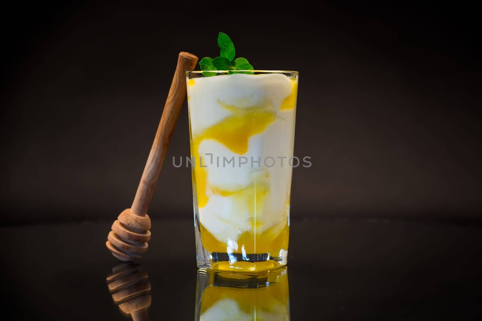 prepared homemade yogurt with natural honey in a glass isolated on a black background.