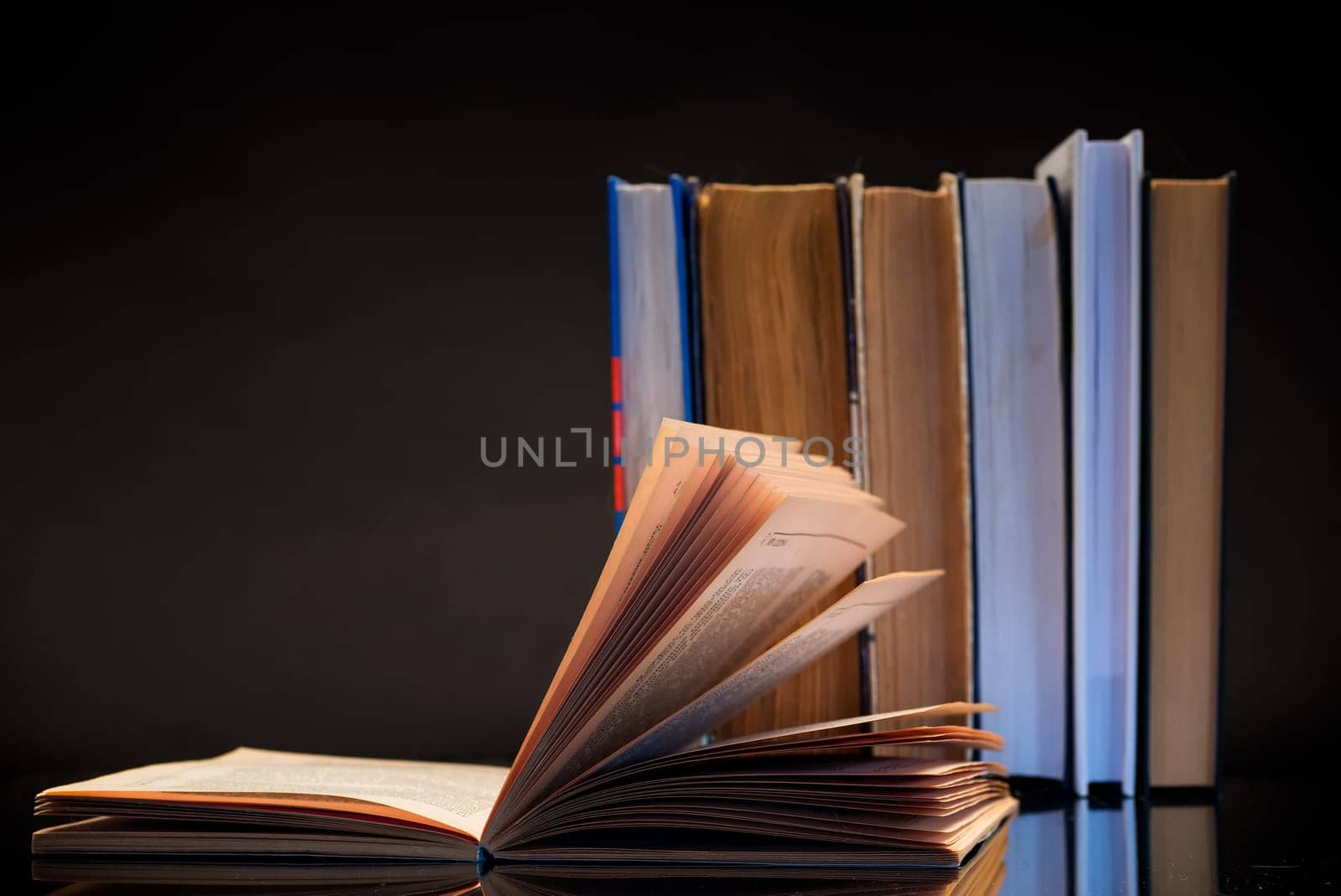open book for reading and a stack of books, isolated on a black background.
