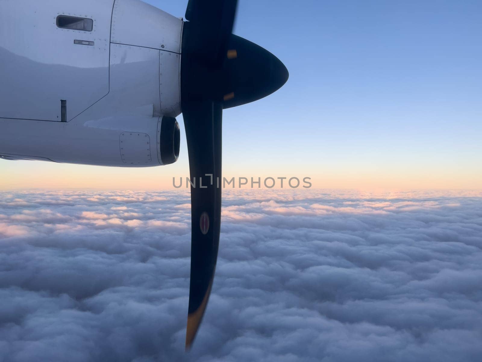 Rotating propeller of an airplane flying above the clouds in the sunset sky. High quality photo