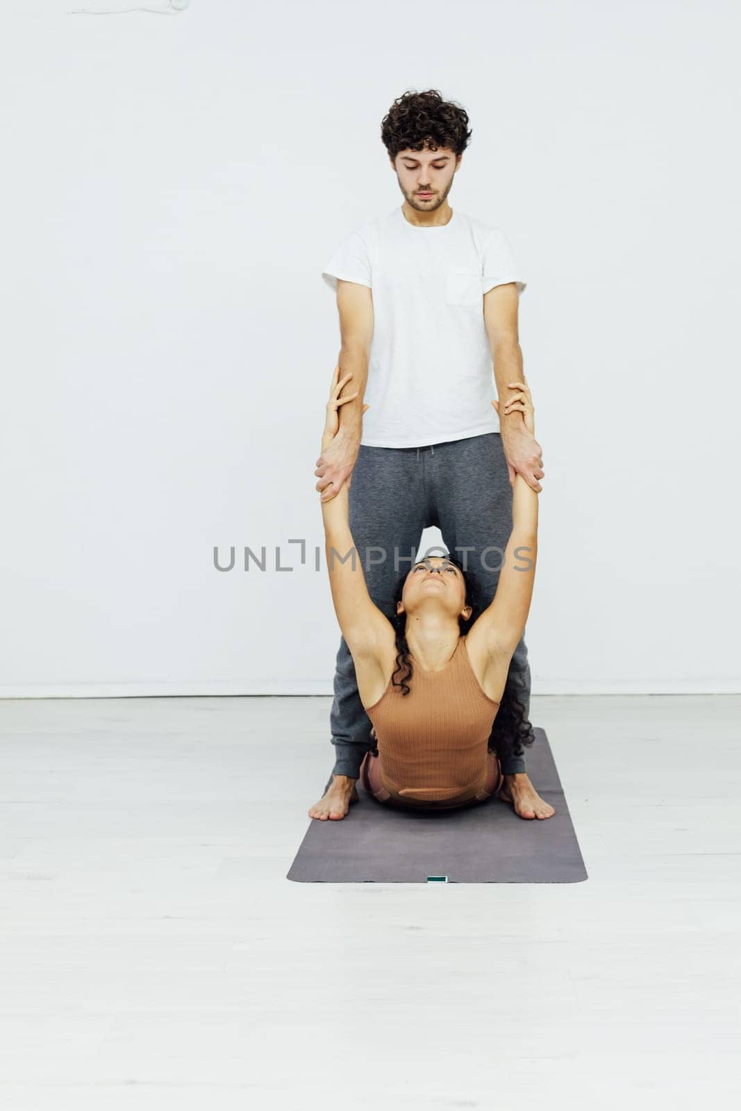 Smiling couple doing yoga exercises outdoors at the beach pier